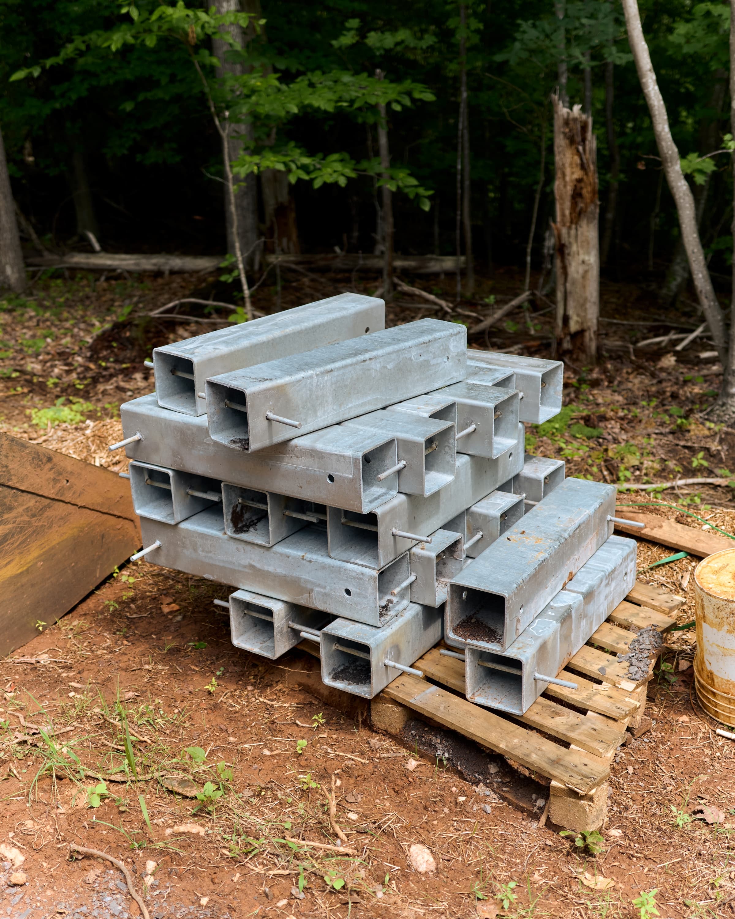 Galvanized steel post-base hardware, stacked and ready to receive the timber frame's posts.